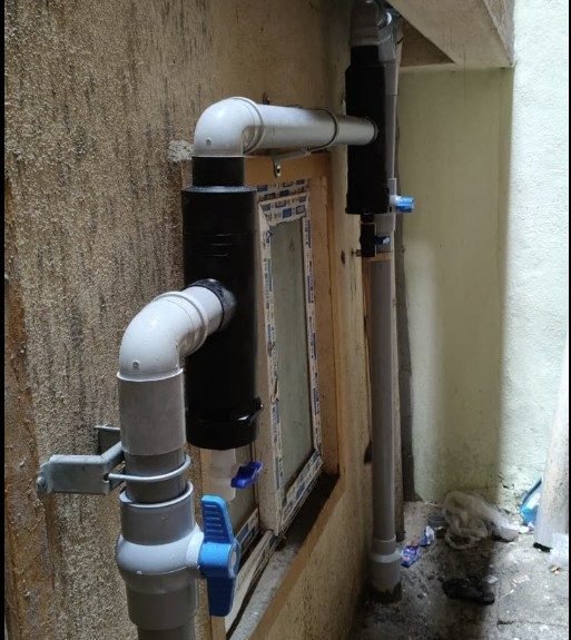 Dual-downpipe rainwater harvesting filter system installed at Electronic City property, with PVC piping and isolation valves